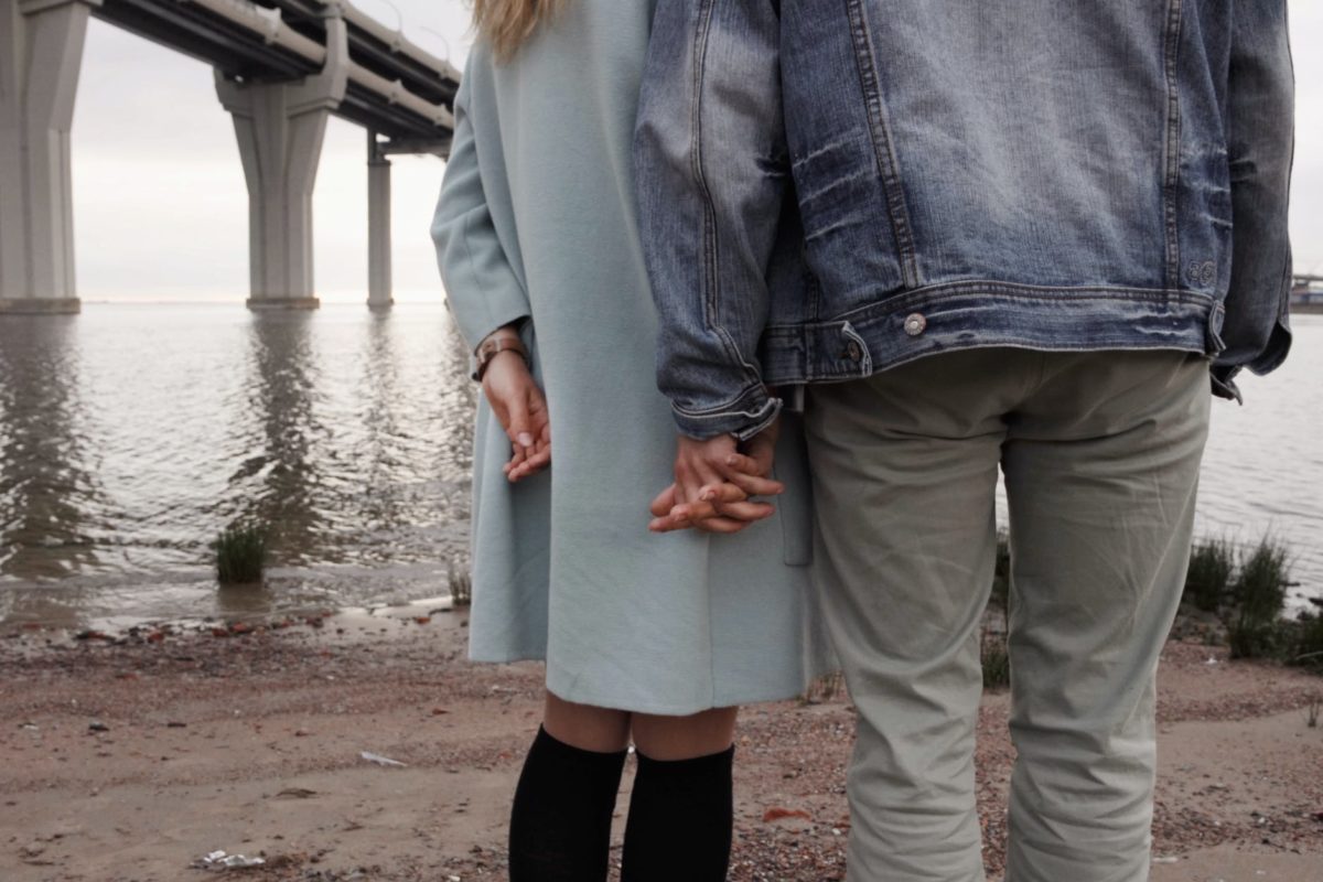 man and woman holding hands near body of water