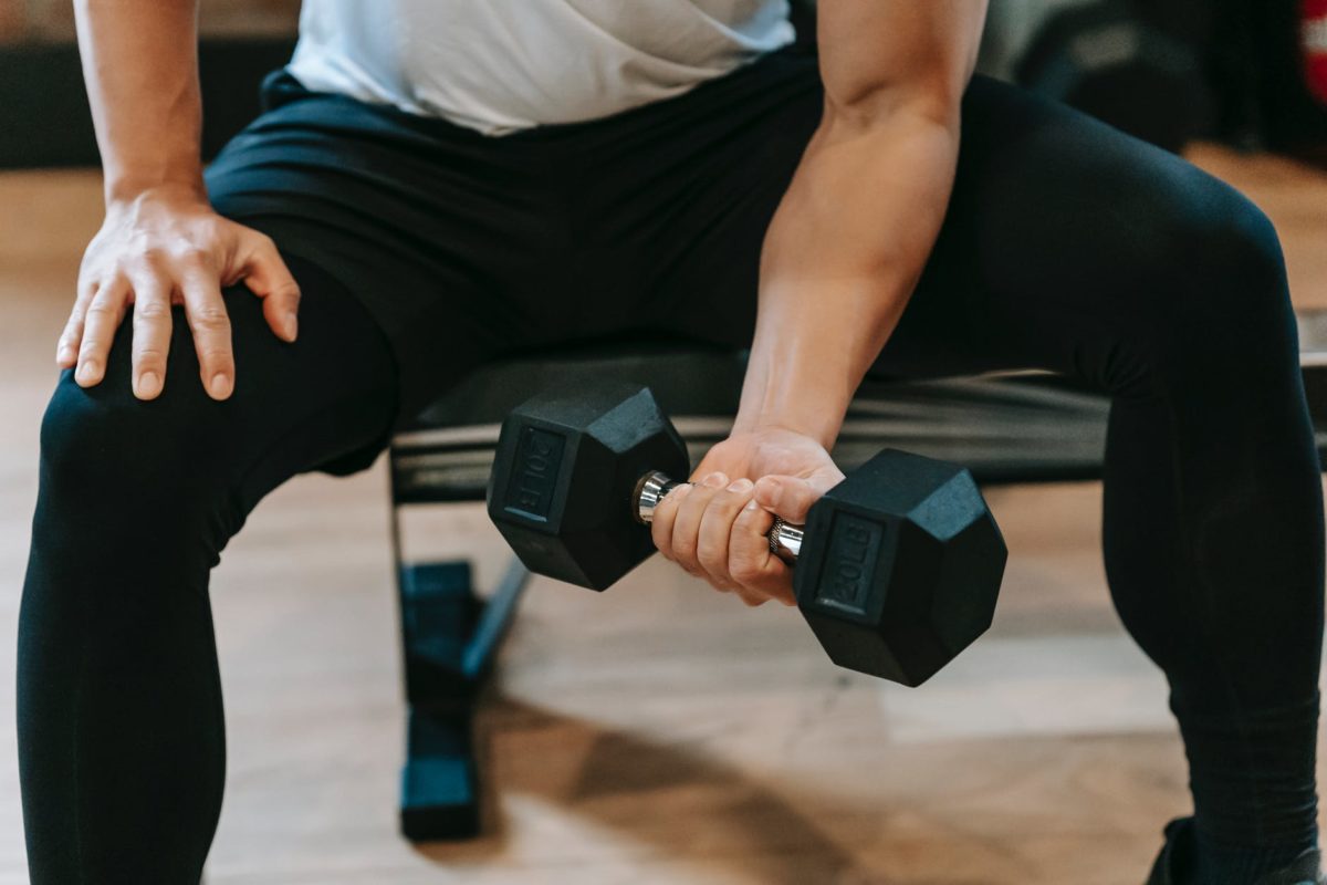 crop man lifting dumbbell on bench